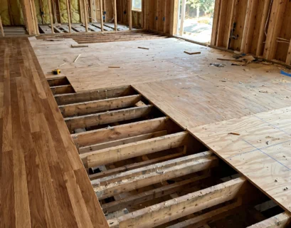 exposed plywood subfloor over floor joists next to finished hardwood flooring