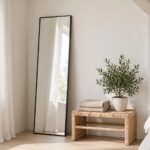 Tall thin-framed long mirror leaning against a bedroom wall